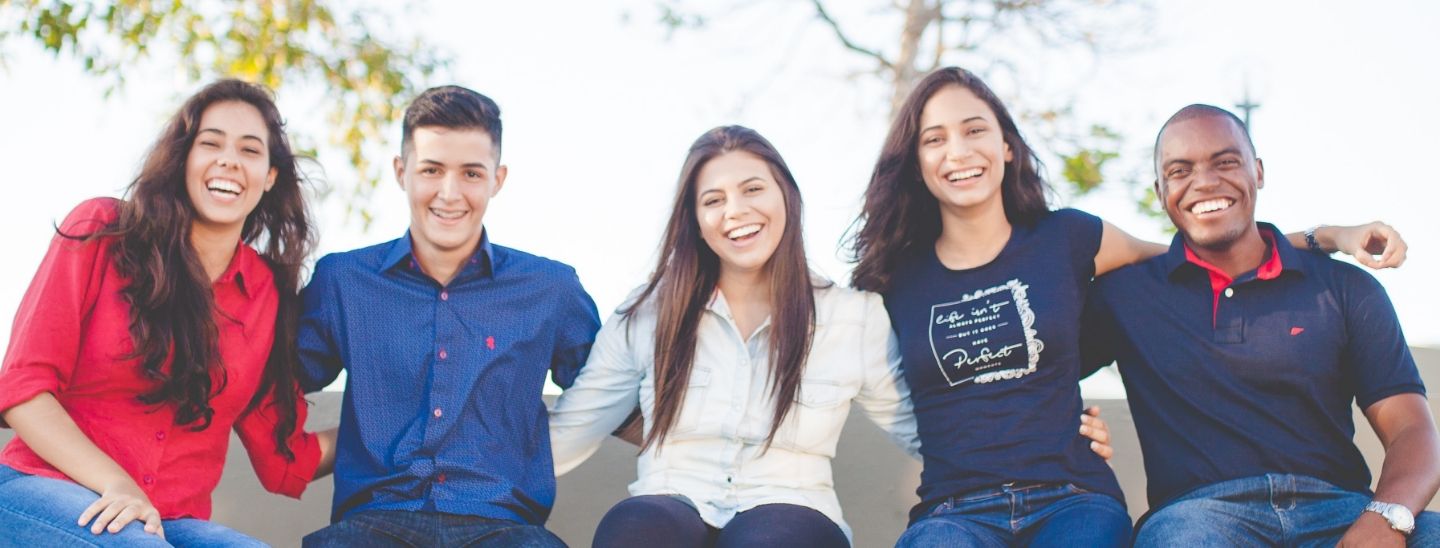Students sitting together outside smiling