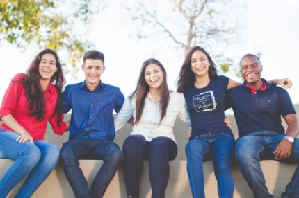 Students sitting together outside smiling